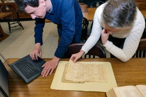Gabriel Raeburn and Christine Bachman-Sanders inspect physical and digital archival documents.