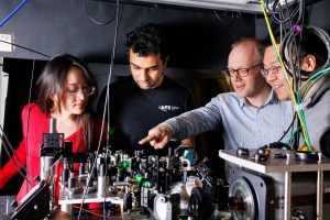 Chris Laumann (second from right), an associate professor of Physics at Boston University, points to a research instrument as Graduate students Esther Wang and Srinivas Mandyam, and Norman Yao.