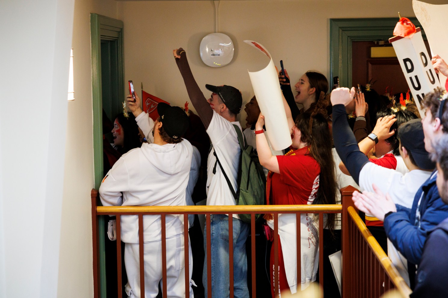 Students rush through the door of a dorm to give a student their housing results.