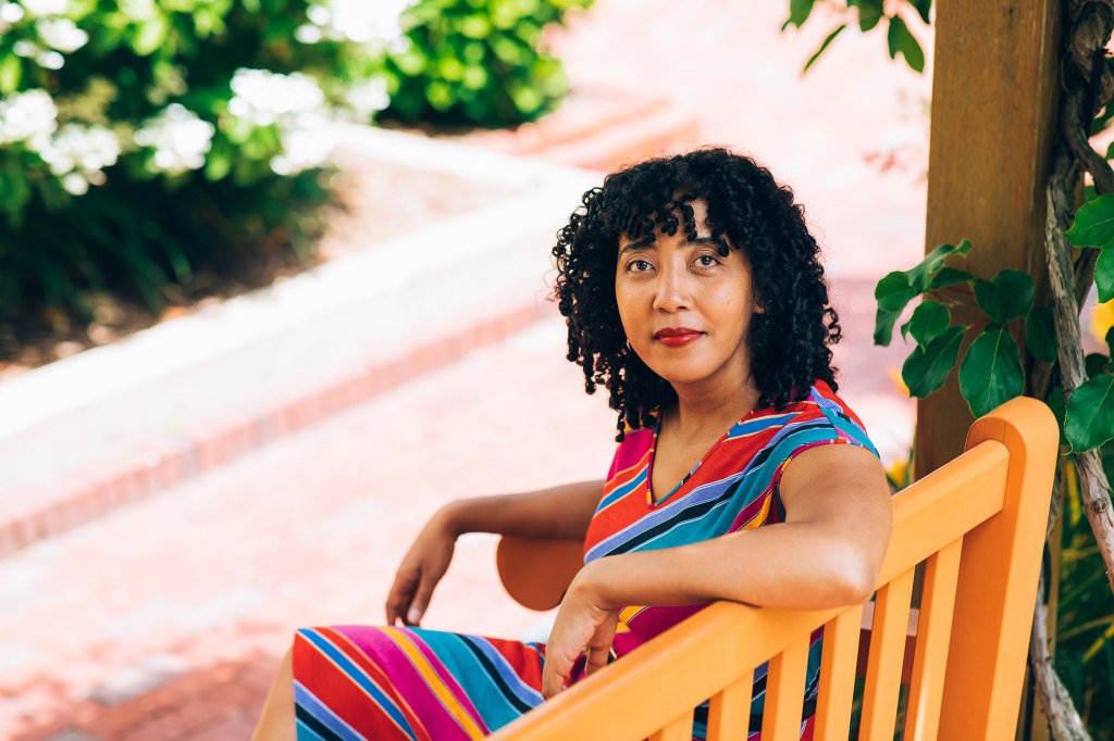 Namwali Serpell sitting on a bench outside.