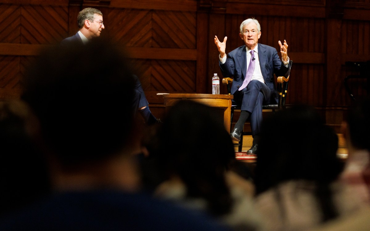 Jerome Powell (right) speaks to a class in Sanders Theatre. He was joined by David Laibson,